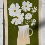 White cosmos flowers in stripe modern vase against green brushstroke background.
