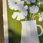 White cosmos with yellow in modern stripe vase in pink and off white with green background.