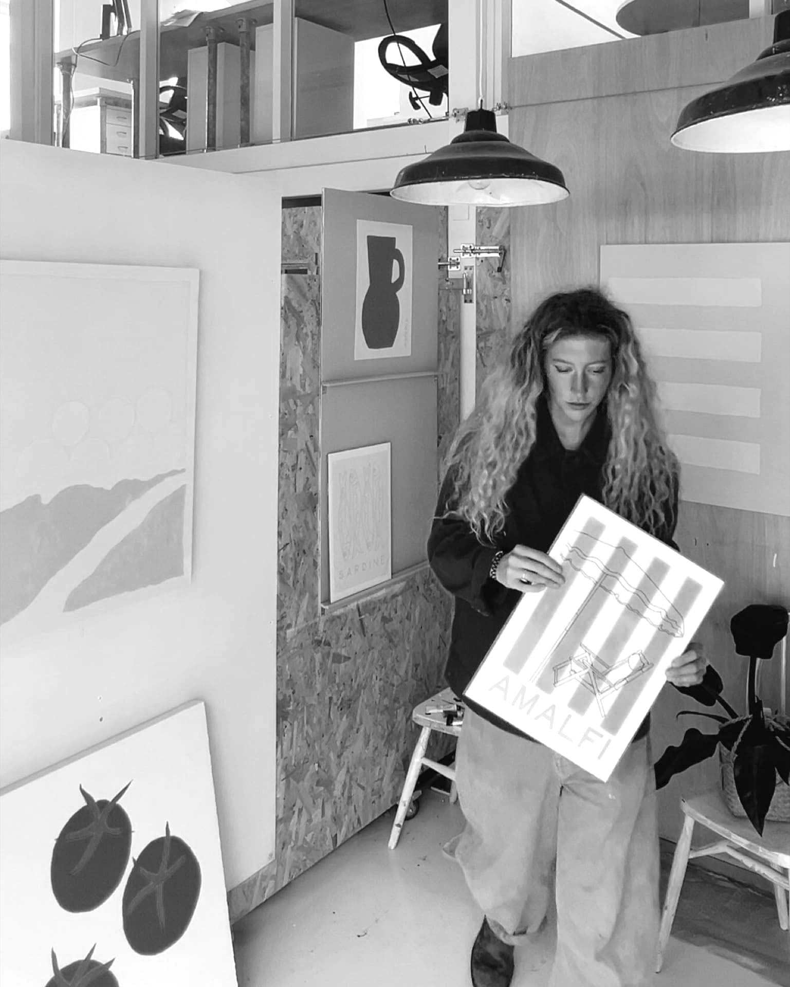 artist mads in falmouth studio holding painting and art print of amalfi coast beach stripe