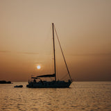 sail boat with mast anchored at sunset floating on med sea
