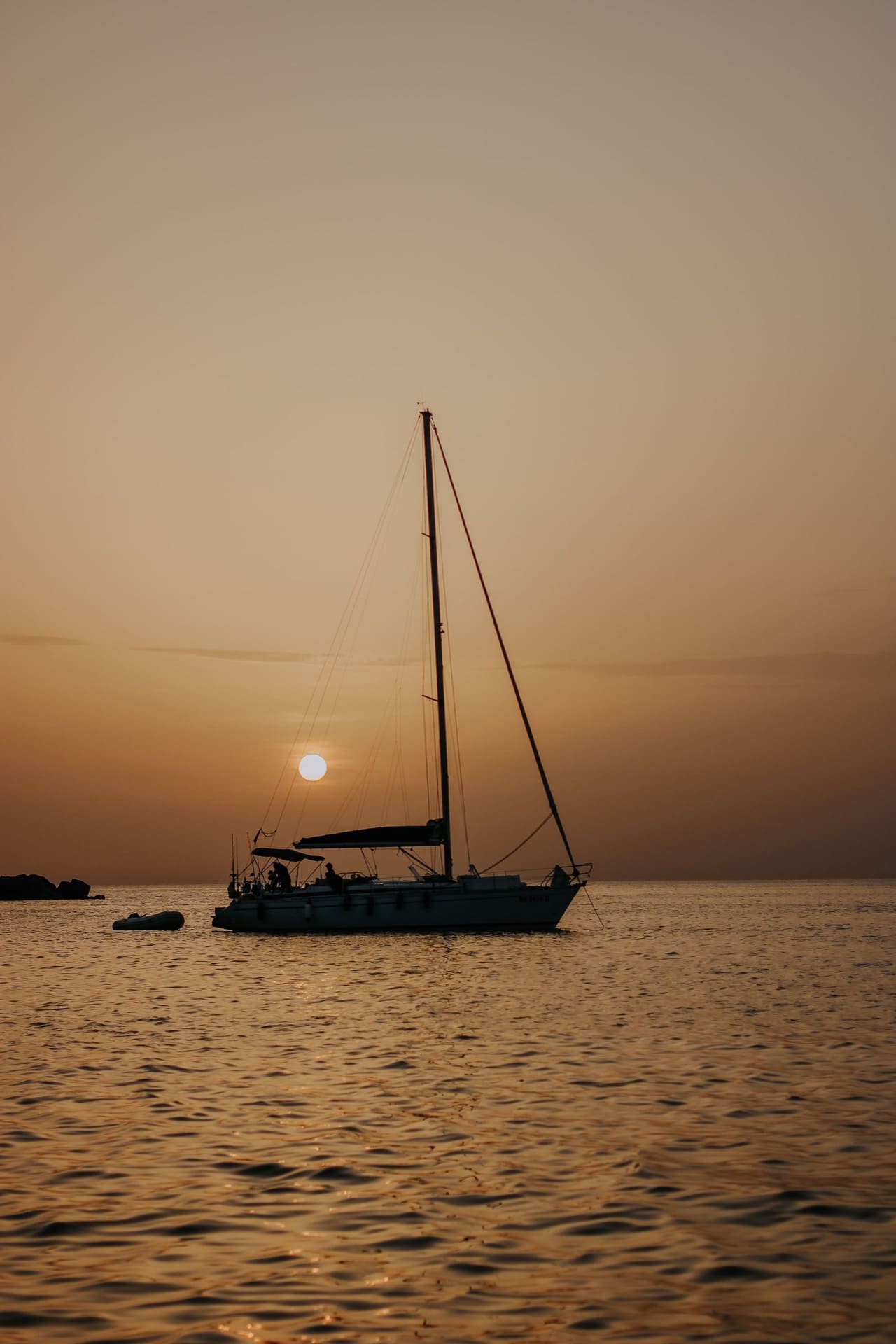 sail boat with mast anchored at sunset floating on med sea