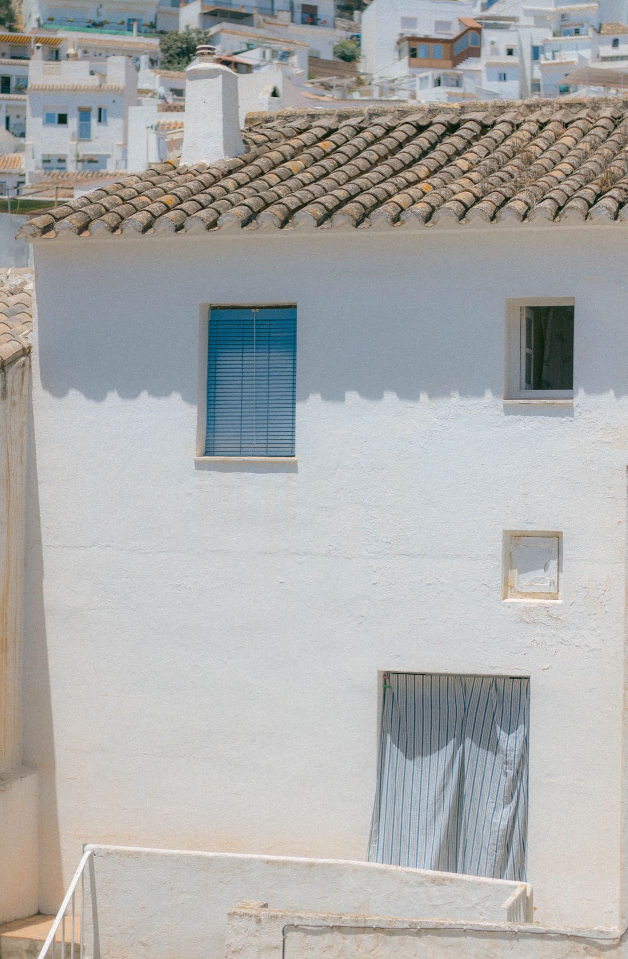greek hilltop buildings in blue and white clay with small windows and linens